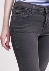 Grå denimjeans med smal passform, klassisk femfickdesign, subtil textur och dragkedja, med sömmar i mörk tråd.