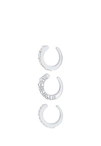 Tre orecchini a cerchio in argento con diverse decorazioni: uno con pietre trasparenti, uno con un bordo testurizzato e uno con delle protuberanze tonde.