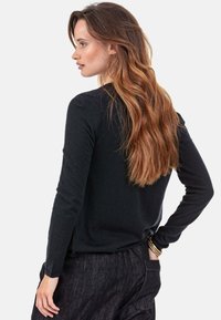 Schwarzer Langarmpullover aus weichem Material mit taillierter Passform, rundem Ausschnitt und dezenten Rippstrukturen an Ärmeln und Saum.