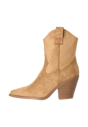 Botín cowboy de ante color beige con puntera puntiaguda, tacón de bloque apilado y lengüeta en la caña sobre fondo blanco.