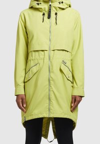 Limegrön, vattentät jacka med dragkedja fram, huva och två stora framfickor. Har en längre bakre nederdel och kontrasterande dragkedjor.