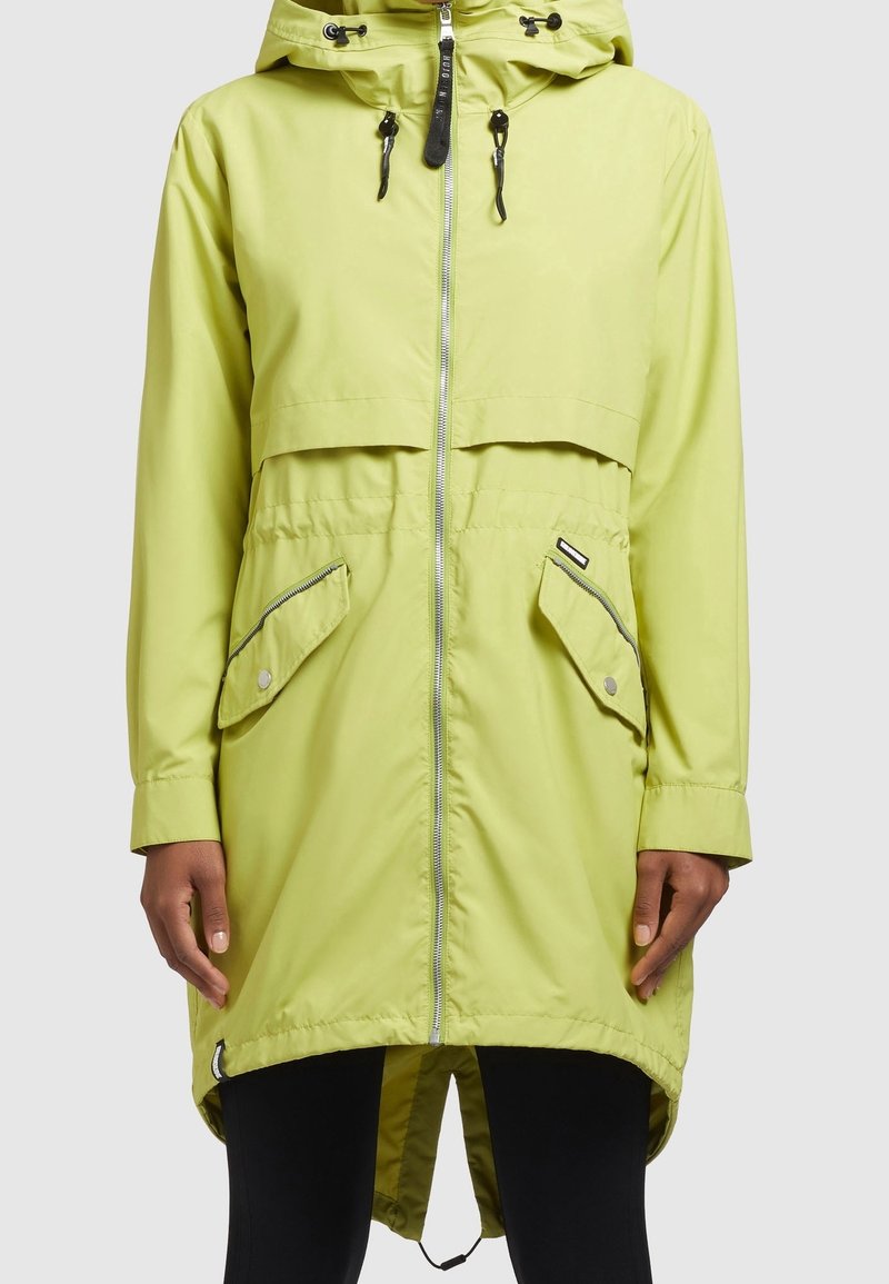 Limegrön, vattentät jacka med dragkedja fram, huva och två stora framfickor. Har en längre bakre nederdel och kontrasterande dragkedjor.