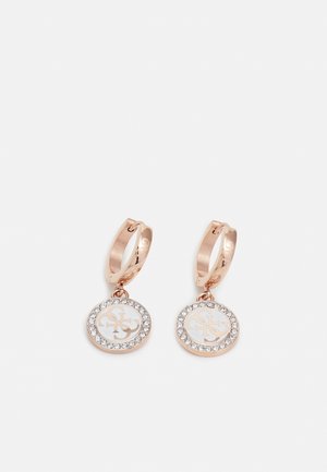 Rose gold hoop earrings with round white pendants featuring a gold monogram and a border of small clear crystals.