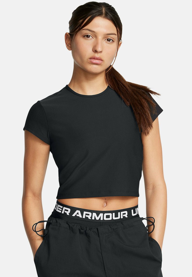 Čierny rebrovaný crop top s krátkymi rukávmi, s okrúhlym výstrihom. Nosený s čiernymi nohavicami, ktoré majú biely pás "Under Armour".