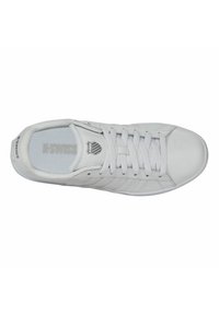 Sneaker bianco con tomaia in pelle liscia, fodera in rete testurizzata, lacci piatti e dettagli del logo sottili. Presenta una punta arrotondata e suola piatta.