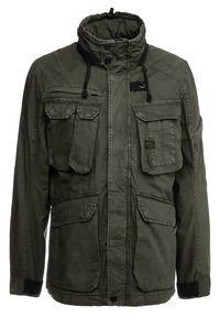 Olivgrön jacka med hög krage, flera framfickor, dragkedja och knappstängning samt snörningsjusteringar. Klassisk militärdesign.