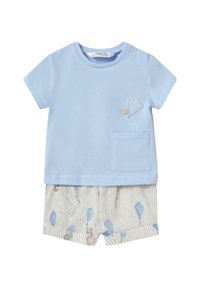 Camiseta de algodón azul claro con un bolsillo, combinada con pantalones cortos rayados beige claros que presentan un patrón divertido de cometas y animales adorables.