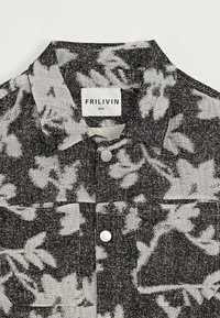 Chemise à manches courtes avec un motif floral abstrait noir et blanc. Présente un col, des boutons sur le devant et une poche poitrine. L'étiquette indique "FRILIVIN."