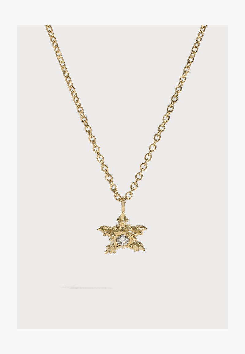 Collier chaîne en or avec un pendentif texturé en forme d'étoile, comportant une pierre précieuse ronde claire au centre sur un fond clair uni.