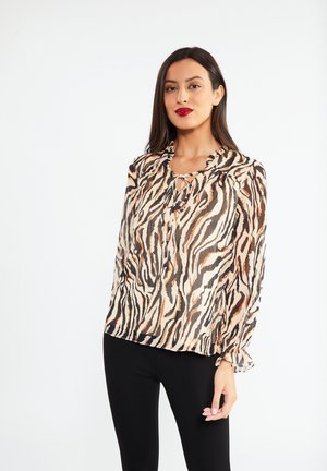 Blusa con stampa animale in tessuto trasparente. Presenta un colletto arricciato e un dettaglio con fiocco sullo scollo. I colori includono beige, arancione e nero.