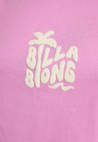 Tessuto rosa con testo bianco in rilievo che forma la sagoma di una palma e le parole "Billabong" in lettere stilizzate e tondeggianti.