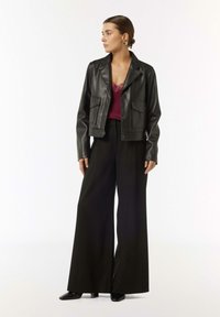 Cropped black leather jacket with two front pockets, paired with a burgundy lace-trimmed top and high-waisted black wide-leg trousers.
