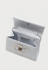 Srebrna błyszcząca torebka kopertowa z metalowym zapięciem i detalami z cyrkonii. Wyposażona w podszewkę wnętrze zawiera kieszeń oraz odczepiany łańcuszek.