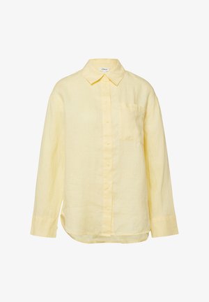 Chemise jaune pâle à manches longues avec col pointu et poche poitrine, fabriquée dans un tissu doux légèrement texturé.