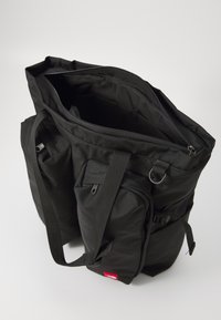 Czarna torba na ramię z wieloma przegrodami, w tym zamykaną na zamek główną komorą, bocznymi kieszeniami i solidnymi ramiączkami.