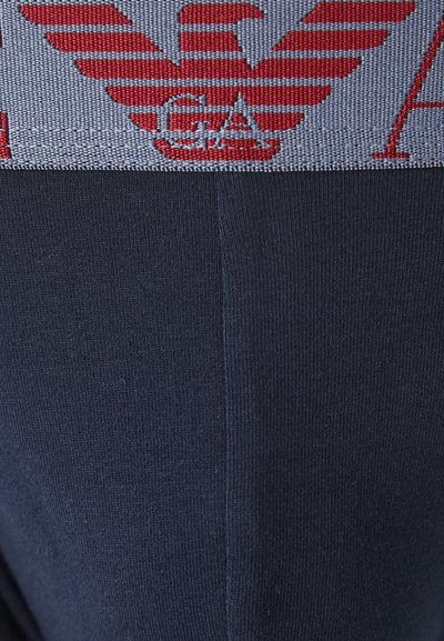 Tissu stretch bleu marine avec une taille plate arborant un design graphique gris et rouge, incluant les lettres "GA" et des accents d'ailes.