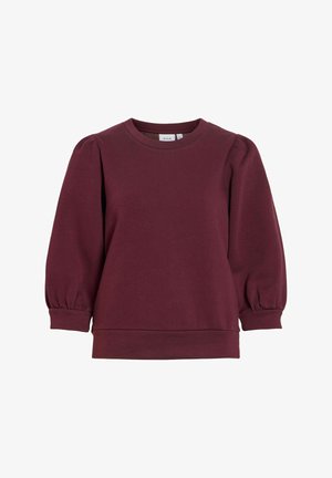 Duks s okruglim izrezom u tamnoljubičastoj boji s napuhanih dugim rukavima i uskim manžetnama, prikazuje jednostavan ležeran stil.