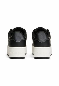 Zapatillas bajas sintéticas negras con talón texturizado, suela plataforma blanca y logotipo en relieve en la parte trasera. Interior forrado para mayor comodidad.