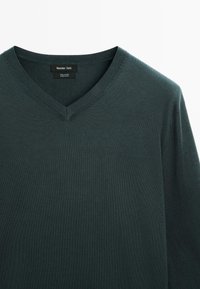 Maglione verde scuro a V realizzato in 100% cotone, con un colletto a coste e una consistenza liscia, dotato di un’etichetta sul colletto.