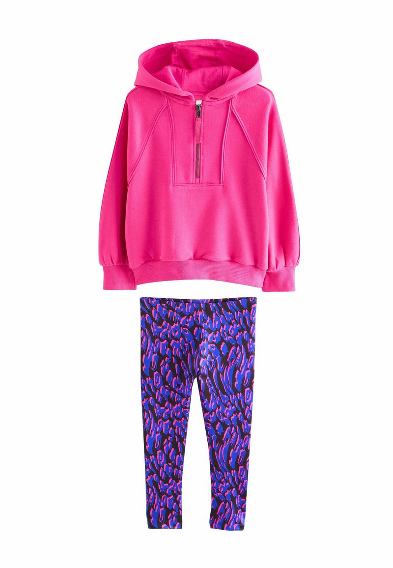 Ljusrosa zip-up hoodie med bred halsringning och rynkade ärmar, kombinerad med lila leggings med ett djärvt djurtryck.