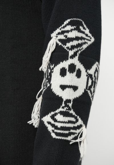 Maglione nero con motivo a maglia bianca che presenta un design di due caramelle e dettagli fru-fru sulle maniche. Texture a costine e materiale morbido.
