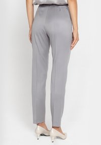 Szare eleganckie spodnie o gładkiej fakturze, z dopasowaną talią i slim fit. W połączeniu z jasnymi, szpiczastymi obcasami.