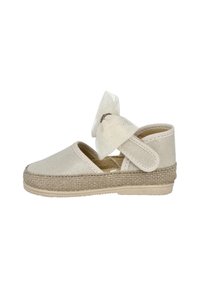 Zapato espadrille beige con suela de yute trenzada, parte superior de tela suave y un lazo de malla blanca. Cuenta con una correa ajustable para un ajuste seguro.