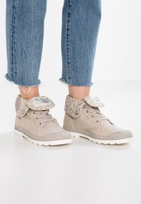 Sneaker high-top beige con colletto in tessuto a fantasia, punte in gomma e suola bianca. Design con lacci e logo sulla linguetta e sul colletto.