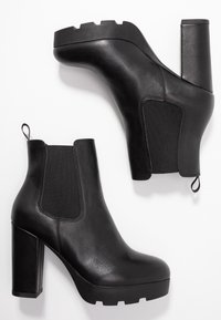 Bottes de cheville en cuir noir avec plateforme et talons carré, présentées en vue latérale et vue de la semelle sur fond blanc.