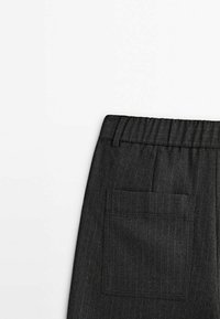 Pantalon gris foncé à fines rayures avec une taille élastique et une grande poche plaquée carrée à l'arrière, côté droit.