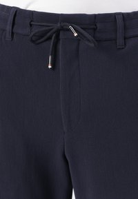 Navyblauwe geribde joggers met een elastische tailleband en verstelbare trekkoorden, voorzien van zilverkleurige accenten. Zijkant met zichtbare zak.