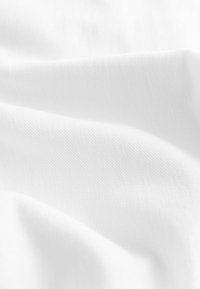 Biely textil s hladkou štruktúrou a jemným diagonálnym tkanie, vykazujúci jemné záhyby a tiene. Ideálny na rôzne použitia.