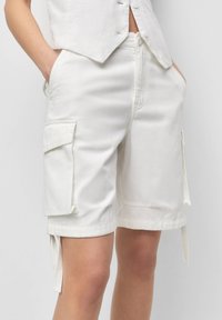 Pantaloni cargo bianchi in cotone con due tasche laterali, orli arrotolati e lacci regolabili sui lati per una vestibilità e un dettaglio raffinato.