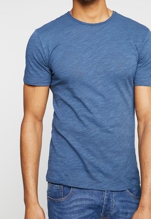 Helles blaues Rundhals-T-Shirt aus strukturiertem Stoff, taillierte Passform, kurze Ärmel und saubere Kanten, kombiniert mit blauen Denim-Jeans.