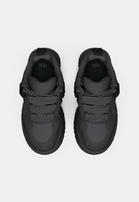 Grå sportskor med texturerad ovandel, tre par grå skosnören och en dragflik. Mjuk dämpning runt ankeln för komfort.