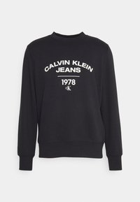 Felpa nera in misto cotone, con testo bianco "CALVIN KLEIN JEANS 1978" in carattere grassetto, scollatura rotonda e polsini a costine.