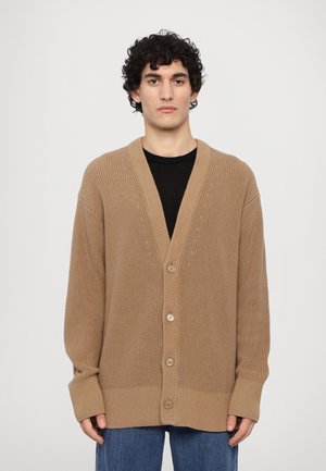 Beige knitted cardigan with a V-neck, ribbed cuffs, and five buttons, featuring a textured pattern throughout the fabric. Casual fit.