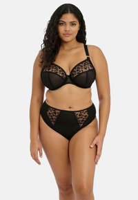 Set di lingerie nera che presenta un reggiseno con coppe in rete a stampa leopardata e una mutanda alta con dettagli in rete. Tessuto liscio con rifiniture delicate.