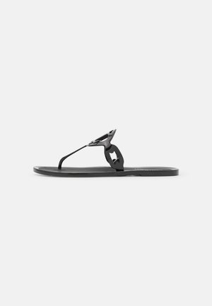 Sort flad tanga-sandal med blank finish og geometrisk udskåret rem på hvid baggrund.
