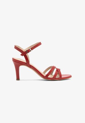 Sandalia de tacón alto de cuero rojo con tiras cruzadas, hebilla plateada en la correa del tobillo ajustable y plantilla de color beige.