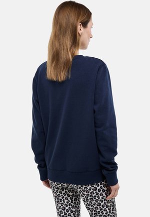 Sweat-shirt bleu marine en tissu doux avec un col rond, une coupe décontractée et des poignets côtelés, associé à des leggings imprimés léopard.