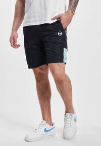 Pantaloni scurți sport negri cu panouri laterale teal, logo pe partea din față stângă, asortați cu adidași albi cu accente de albastru deschis.