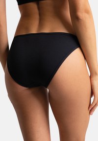 Bas de bikini noir à taille haute et côtelé, présentant une texture lisse et des ouvertures de jambe courbes, avec un design minimaliste et sans fermetures visibles.