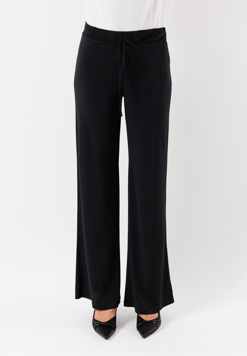 Pantaloni neri a gamba larga con vita regolabile e tessuto liscio. Abbinati a tacchi a spillo neri. Design semplice e funzionale.