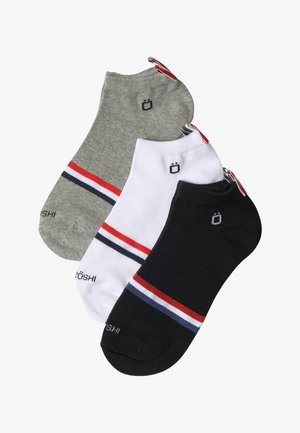 Tres calcetines tobilleros en gris, blanco y negro, cada uno con rayas rojas, blancas y azul marino y un pequeño logotipo negro cerca del puño del tobillo.