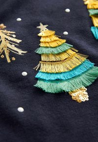 Design di un albero di Natale ricamato con frange in verde e oro su uno sfondo scuro, arricchito da perline bianche e paillette.