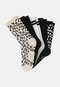 Sæt med otte strømper med forskellige designs: én beige med sorte leopardpletter, flere ensfarvede sorte, samt to med striber og mønstre i hvid og sort.