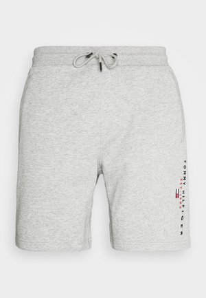 Pantalones cortos de algodón gris claro con cintura ajustable, bolsillos laterales y una marca vertical de Tommy Hilfiger en la pierna derecha.