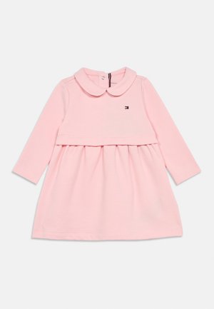 Roza dolga obleka z dolgimi rokavi, okroglistim ovratnikom, nabranim pasom in malim logotipom na prsih. Narejena iz mehkega materiala, ponuja sproščen kroj.