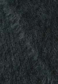 Donkergroene, fuzzy stof met een zachte, harige textuur; heeft variërende lengtes van vezels die diepte en een rijke, gelaagde uitstraling creëren.